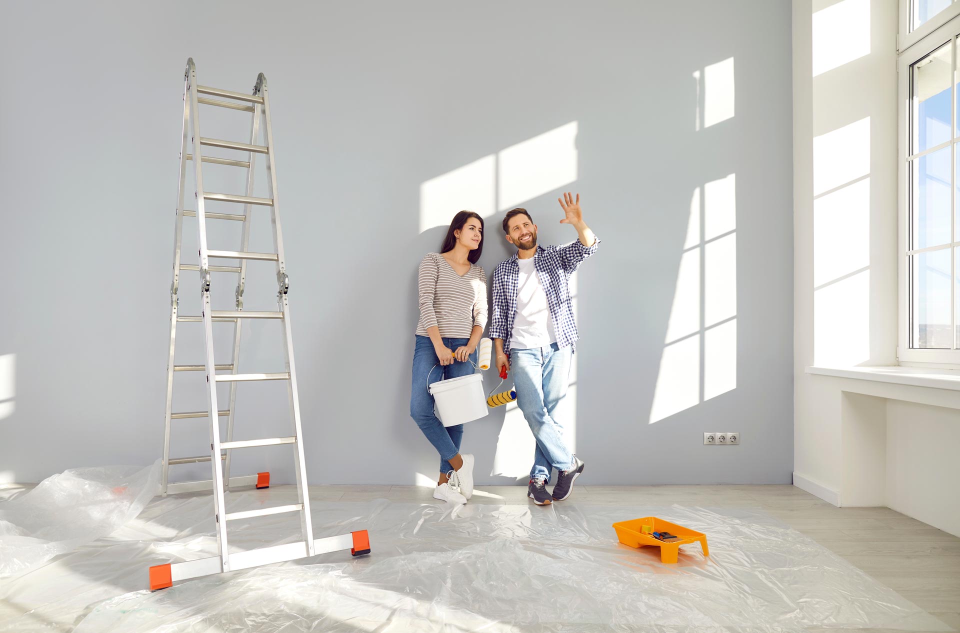 Couple discussing construction plans while leaning on a wall and surrounded by tools